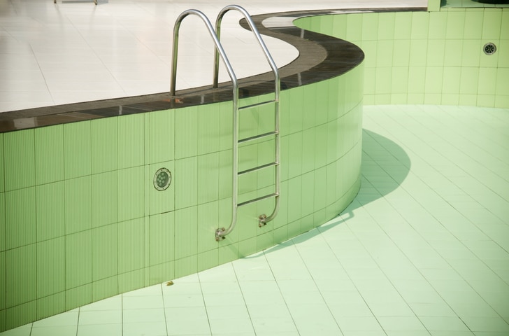 An empty swimming pool with metallic stairs isolated unique photo